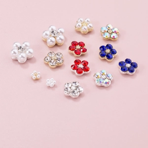 Colorful floral nail art charms with pearls and crystals on a soft pink background