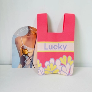 Detailed knit texture of pink tote bag with floral patterns and Lucky letter embroidery