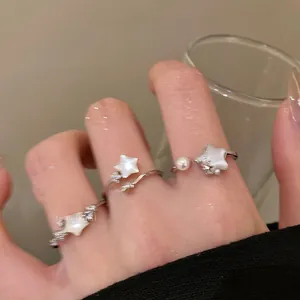 Close-up of silver star-shaped shell ring with pearls and zircon on model finger