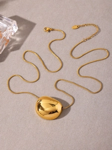 Detailed view of polished 18k gold bean pendant on minimalist stainless steel chain