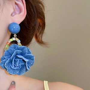 Détail de boucles d'oreilles rose en denim avec perles bleues portées à l'oreille