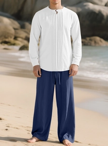 Détail d'une chemise plissée blanche et d'un pantalon bleu sur une plage