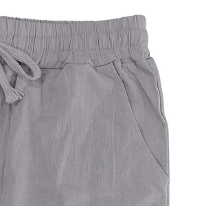 Detail of grey linen trousers featuring elastic drawstring waist and side pockets