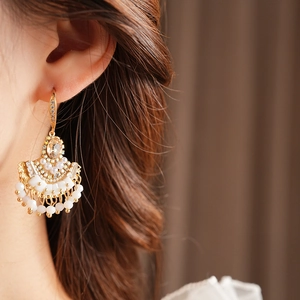 Gros plan de boucles d'oreilles en éventail vintage avec zircons, perles et glands fins