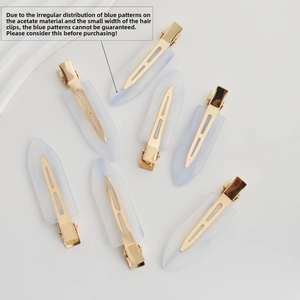 Close-up of minimalist blue acetate hair clips with golden metal base on cream background