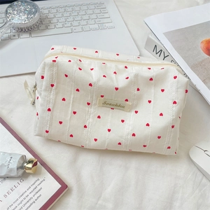 Macro view of white striped makeup bag with red hearts and smooth zipper details