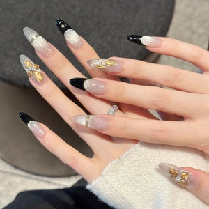 Unghie nere a mandorla con fiocco dorato 3D, effetto cat-eye e accenti di glitter argento