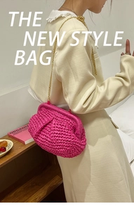 Detail of rose red woven dumpling bag with elegant gold chain strap worn by a model