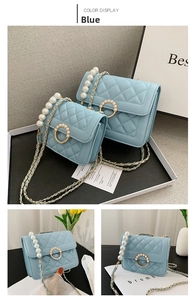 Detail of light blue quilted chain bag with pearl handle and golden hardware buckle