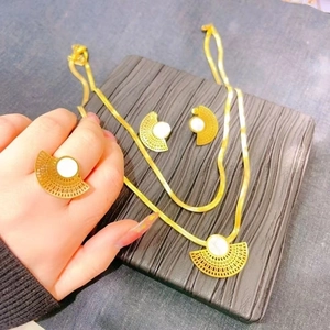 Detail of fan-shaped gold jewelry set with white shell inlay on necklace, earrings, and ring