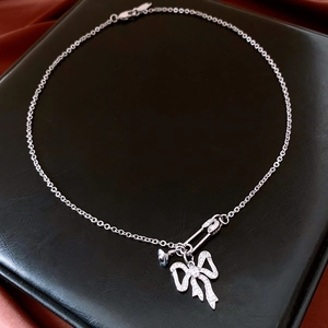 Macro view of silver paperclip bow necklace with pavé cubic zirconia on leather box