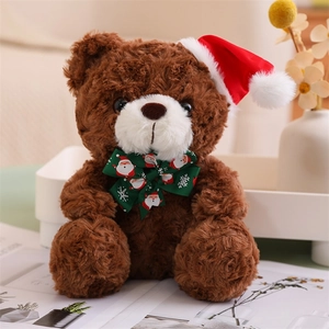 Detail of a brown teddy bear with a red Santa hat and green bow in a cozy indoor setting