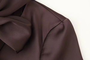 Detailed macro view of dark coffee satin dress showing smooth silky fabric texture