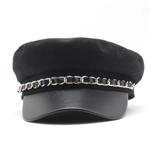 Detail of black wool newsboy cap featuring faux leather brim and silver metal chain link