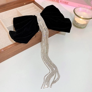 Detail of elegant black velvet bow hair clip with long sparkling rhinestone tassels