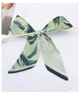Detailed macro of a green floral silk ribbon tied as a bow on a white background