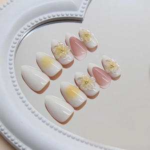 Press-on nails in white and pink gradient with 3D floral accents and golden beads