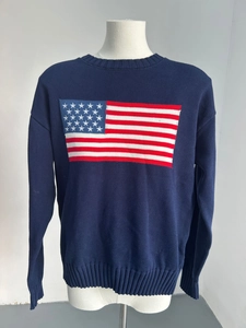 Detailed close-up of navy blue knit sweater showing American flag pattern and ribbed cuffs