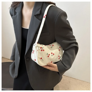 Close-up of stylish corduroy underarm bag featuring red cherry print and zipper detail