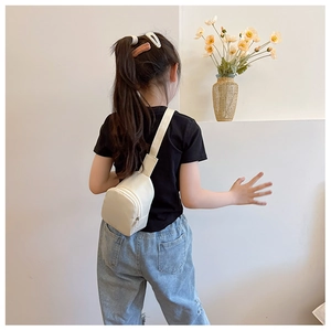 White mini crossbody chest bag for kids worn by a model in a lifestyle setting