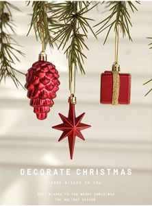 Close-up of red pine cones and gift box ornaments hanging on green Christmas tree branches