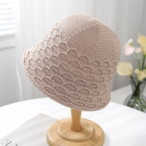 Elegant beige hollow out crochet knit bucket hat displayed on a wooden stand