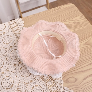 Detail of pink straw sun hat with wavy scalloped edges and adjustable windproof strap