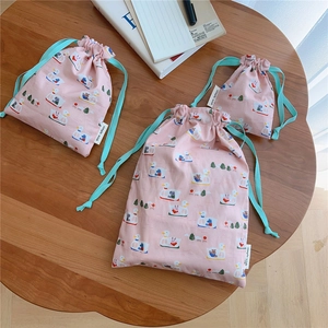Three-piece set of pink cotton drawstring bags with cute duck prints on a wooden desk