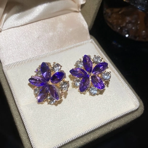Close-up of purple flower crystal earrings with gold base in a velvet jewelry box