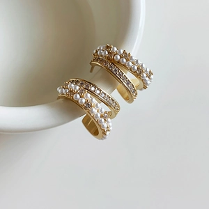 Detail of 14k gold plated C-shaped earrings with rows of pearls and zircon stones