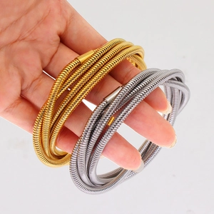 Detail of gold and silver multi-layer coiled snake-style elastic bracelets on hand