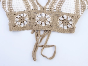 Close-up detail of crochet knit halter top with hollow flower patterns and tie straps