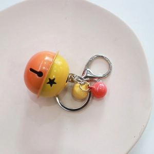 Close-up of vibrant candy-colored metal bells with star cutouts on woven rope keychain