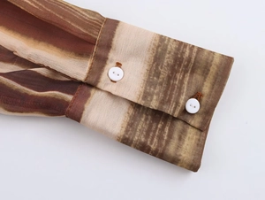 Dettaglio del polsino con doppio bottone della camicia in chiffon a righe marroni