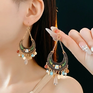 Detail of bohemian moon earrings with green enamel and water drop crystal pendants
