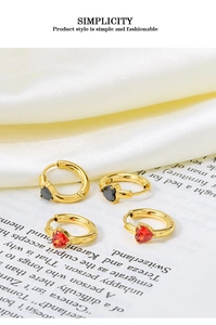 Close-up of red and black heart-shaped zircon earrings on elegant white satin fabric