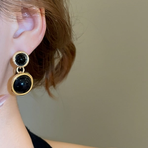 Detailed view of model wearing gold black resin round drop earrings in French palace style