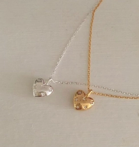 Close-up of gold and silver heart necklaces with micro-inlaid zircon pendants