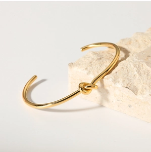 Dettaglio del bracciale aperto minimalista con nodo placcato oro 18K su una pietra