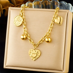 Detail of a gold multi-pendant bracelet with rose engraving and flame heart charms