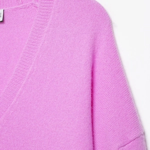Pale pink V-neck knit sweater in soft plush fabric with ribbed collar and shoulder detail