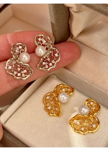 Detail of twisted镂空 earrings with zircons and central white pearls in gold and silver