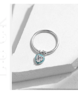 Detailed macro view of silver heart pendant ring with blue enamel and sparkling zircon