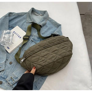 Green quilted nylon crossbody bag with adjustable strap worn over a denim jacket