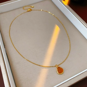 Detail of a gold plated necklace with amber teardrop pendant in a jewelry box