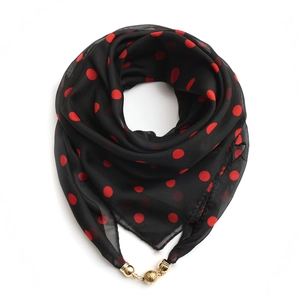 Detailed view of black chiffon scarf with red dots and a textured gold magnetic clasp ball