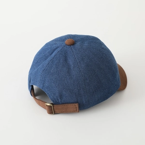 Close-up of denim baseball cap with brown suede brim and adjustable copper buckle