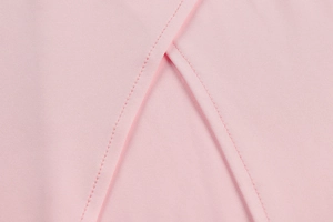 Détail de la fente latérale de robe rose avec double couture de qualité et tissu lisse