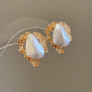 Détail de boucles d'oreilles triangulaires dorées plissées avec incrustation perle