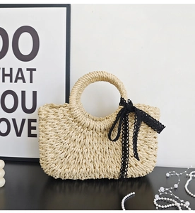 Close-up of woven straw handbag featuring a delicate black lace bow handle and natural texture